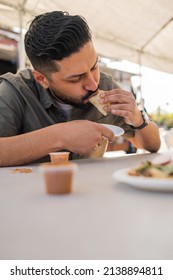 Young Hispanic Man Enjoying A Carnitas Taco Outside