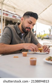 Young Hispanic Man Enjoying A Carnitas Taco Outside