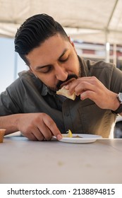 Young Hispanic Man Enjoying A Carnitas Taco Outside