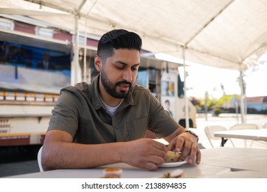 Young Hispanic Man Enjoying A Carnitas Taco Outside