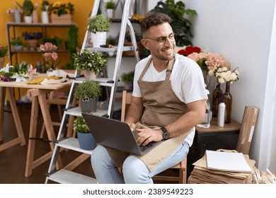 Young hispanic man florist smiling confident using laptop at flower shop - Powered by Shutterstock