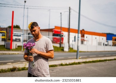 Young Hispanic man with half blonde hair with a bouquet of purple flowers
