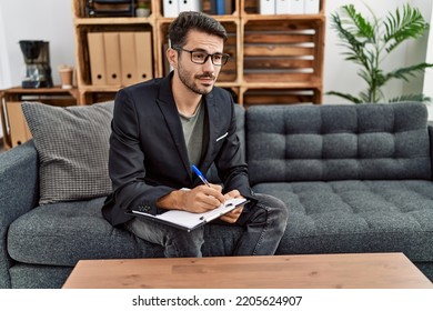 Young Hispanic Man Having Psychology Session Writing On Checklist At Clinic