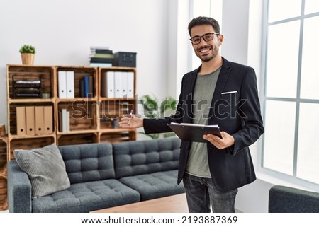 Young hispanic man having psychology session holding checklist welcoming patient at clinic Foto stock © 