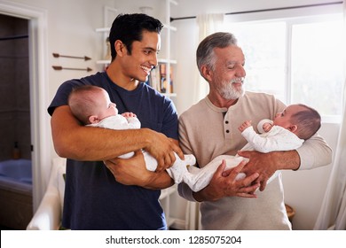 Young Hispanic Man And His Senior Father Holding His Two Baby Boys At Home