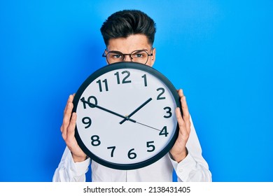 Young Hispanic Man Holding Big Clock Over Face Depressed And Worry For Distress, Crying Angry And Afraid. Sad Expression. 