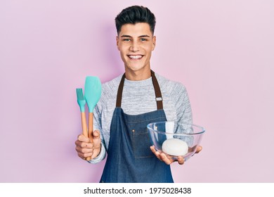 Young hispanic man holding bread dough and cooking tools smiling with a happy and cool smile on face. showing teeth. 