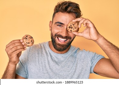 Young hispanic man holding cookie smiling and laughing hard out loud because funny crazy joke. 