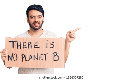 Young Hispanic Man Holding There Is No Planet B Banner Smiling Happy Pointing With Hand And Finger To The Side 