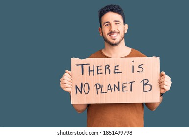 Young Hispanic Man Holding There Is No Planet B Banner Looking Positive And Happy Standing And Smiling With A Confident Smile Showing Teeth 