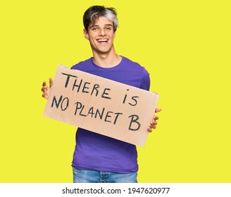 Young Hispanic Man Holding There Is No Planet B Banner Looking Positive And Happy Standing And Smiling With A Confident Smile Showing Teeth 