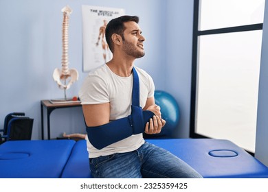 Young hispanic man injured physiotherapy patient suffering for arm pain at rehab clinic