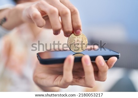 Young hispanic man inserting bitcoin on smartphone at home
