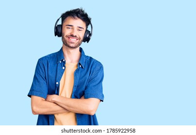 Young Hispanic Man Listening To Music Using Headphones Happy Face Smiling With Crossed Arms Looking At The Camera. Positive Person. 