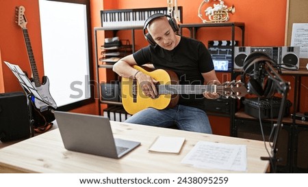 Young hispanic man musician having online classical guitar lesson at music studio