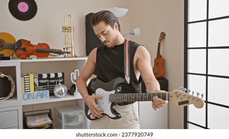 Young hispanic man musician playing electrical guitar with serious face at music studio - Powered by Shutterstock