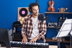 Young Hispanic Man Musician Singing Song Playing Piano At Music Studio