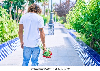 Young hispanic man on back view holding bouquet of roses walking with unhappy expression.