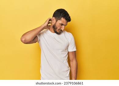 Young Hispanic man on yellow background suffering neck pain due to sedentary lifestyle.