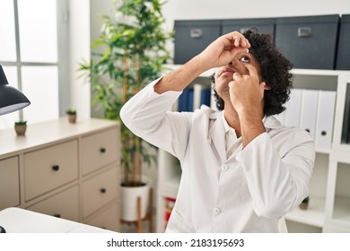 Young Hispanic Man Optician Applying Eye Drop At Clinic