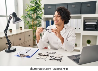 Young Hispanic Man Optician Holding Glasses At Clinic