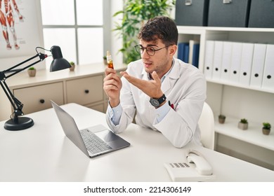 Young Hispanic Man Optician Holding Medication Bottle At Clinic