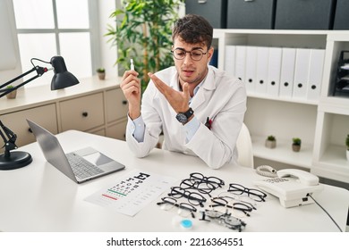 Young Hispanic Man Optician Holding Eye Drops At Clinic