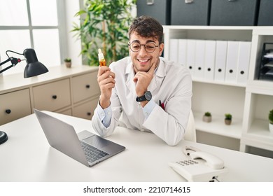 Young Hispanic Man Optician Smiling Confident Holding Medication Bottle At Clinic