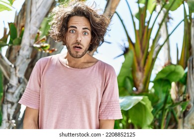 Young Hispanic Man Outdoors On A Sunny Day Scared And Amazed With Open Mouth For Surprise, Disbelief Face 