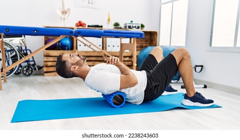 Young hispanic man patient smiling confident having back rehab session using foam roller at clinic - Powered by Shutterstock