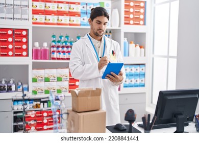 Young Hispanic Man Pharmacist Using Touchpad Working At Pharmacy