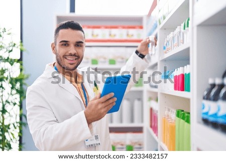 Young hispanic man pharmacist using touchpad working at pharmacy