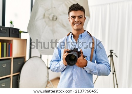 Young hispanic man photographer using professional camera at photography studio
