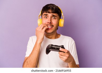 Young hispanic man playing with a video game controller isolated on purple background biting fingernails, nervous and very anxious. - Powered by Shutterstock