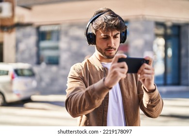 Young hispanic man playing video game at street - Shutterstock ID 2219178097