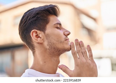 Young Hispanic Man Praying With Closed Eyes At Park