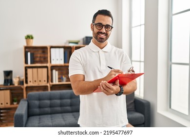 Young hispanic man psychologist writing on clipboard at psychology center - Shutterstock ID 2195477697