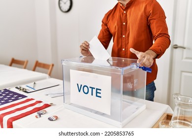 Young Hispanic Man Putting Vote In Box At Electoral College