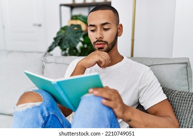 Young Hispanic Man Reading Book At Home