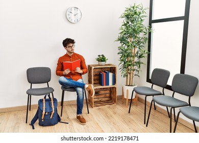 Young Hispanic Man Reading Book At Waiting Room