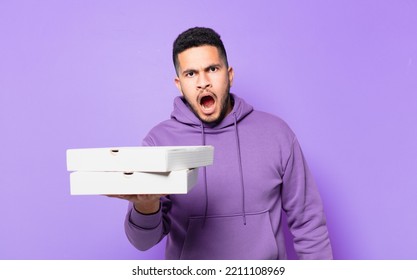 Young Hispanic Man Scared Expression And Holding Take Away Pizzas