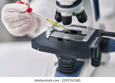 Young hispanic man scientist using microscope working at laboratory