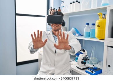 Young hispanic man scientist using virtual reality glasses at laboratory