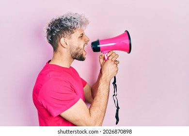 Young Hispanic Man Screaming With Megaphone Over Pink Background