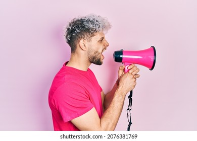 Young Hispanic Man Screaming With Megaphone Over Pink Background