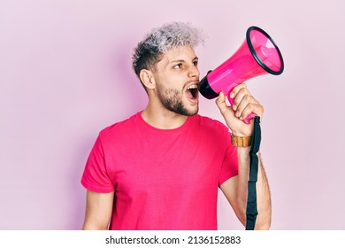 Young Hispanic Man Screaming With Megaphone Over Pink Background