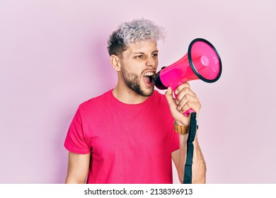 Young Hispanic Man Screaming With Megaphone Over Pink Background