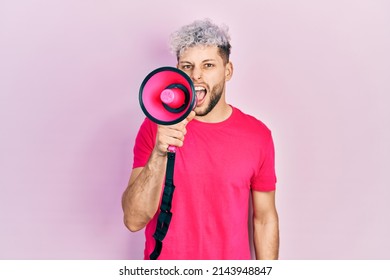 Young Hispanic Man Screaming With Megaphone Over Pink Background