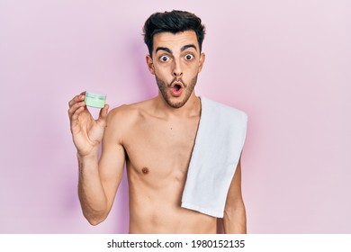 Young Hispanic Man Shirtless Wearing Towel And Eye Bags Patches Scared And Amazed With Open Mouth For Surprise, Disbelief Face 