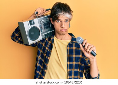 Young Hispanic Man Singing Song Using Microphone And Boombox Depressed And Worry For Distress, Crying Angry And Afraid. Sad Expression. 